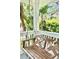 Inviting porch features a wooden swing, white railing, and lush tropical foliage, perfect for relaxing outdoors at 417 S Palmetto Ave, Daytona Beach, FL 32114