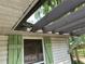 Exterior shot showcasing weathered siding, green shutters, and a damaged roof overhang at 43721 State Road 19, Altoona, FL 32702