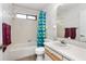 Bathroom with a tub, tiled walls, and a well-lit vanity area. Includes colorful shower curtain at 71 Crooked Pine Rd, Port Orange, FL 32128