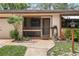 Charming front entrance with a screened porch, rock landscaping, and decorative light fixture at 71 Crooked Pine Rd, Port Orange, FL 32128