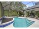 Screened-in pool area with a uniquely-shaped pool, ample patio space, and lush greenery at 940 Glenwood Rd, Deland, FL 32720