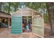 An exterior view of a green corrugated metal shed with open doors revealing tools and equipment inside at 940 Glenwood Rd, Deland, FL 32720