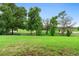 Lush green backyard with mature trees providing privacy and a partial view of a golf course at 978 Victoria Hills S Dr, Deland, FL 32724