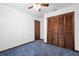 Carpeted bedroom featuring a ceiling fan, white walls, and a closet with wood-paneled doors at 1018 E Gaucho Cir, Deltona, FL 32725