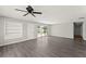 Spacious living room with gray wood floors, built-in shelves, fan, and access to the pool area at 1027 Bel Aire Dr, Daytona Beach, FL 32118