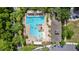 Aerial view of a swimming pool with clear blue water, lounge areas, and surrounded by trees and buildings at 1227 Victoria Hills N Dr, Deland, FL 32724