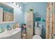 Charming blue bathroom with a vintage cabinet, offering a sink, toilet, and shower with a decorative shower curtain at 127 Cypress Pond Rd, Port Orange, FL 32128