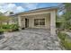 Comfortable outdoor patio with stone pavers, a covered seating area, and lush landscaping at 1310 Pup Fish Ln, Deland, FL 32724