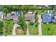 An aerial view of a home with a pool, green lawn, and a paved driveway with mature trees in a sunny neighborhood at 1411 N Beach St, Ormond Beach, FL 32174