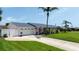 A charming single-story pink home features a well-kept lawn, an attached garage and tropical palm trees at 179 Ann Rustin S Dr, Ormond Beach, FL 32176
