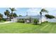 Charming pink single-story home featuring a well-manicured lawn and tasteful landscaping with tropical palms at 179 Ann Rustin S Dr, Ormond Beach, FL 32176