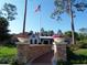 Landscaped pathway leading to the clubhouse with flag pole and flower pots on brick pillars at 202 W Chancery Ln, Deland, FL 32724