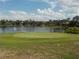 Scenic golf course view with a tranquil lake, framed by lush greenery under a bright, partly cloudy sky at 217 Lourdan Ct, Debary, FL 32713