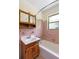 Bathroom features pink tile, wood vanity, and a shower-tub combo at 220 N Julia Ave, Deland, FL 32720