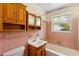 Bathroom features pink tile, wood vanity, and a window for natural light at 220 N Julia Ave, Deland, FL 32720