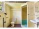 Functional bathroom with a toilet, sink, and walk-in shower, featuring retro yellow block walls and practical fixtures at 220 N Julia Ave, Deland, FL 32720
