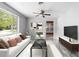 Bright living room features a ceiling fan, a sleek TV console, and contemporary furnishings at 220 N Julia Ave, Deland, FL 32720