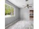Bright living room with light gray walls, wood-look floors, and a large window overlooking the front yard at 220 N Julia Ave, Deland, FL 32720
