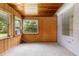 Sunroom featuring wood paneling, carpet flooring, and multiple windows providing natural light and views of the outdoors at 220 N Julia Ave, Deland, FL 32720