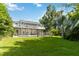 The house's backyard has a sparkling pool, green grass, and tropical landscaping, creating a peaceful retreat at 2250 Davis Dr, New Smyrna Beach, FL 32168