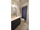 Bright bathroom featuring vanity with gold hardware, illuminated mirror, and a shower with blue pattern curtain at 2380 Spring Hollow Drive, Orange City, FL 32763