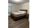 Cozy bedroom showcases a wood-frame bed, neutral bedding, and dark wood floors, creating a warm retreat at 2380 Spring Hollow Drive, Orange City, FL 32763