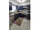 A stylish kitchen featuring navy cabinets, marble-look floors, and stainless steel appliances offers a modern feel at 2380 Spring Hollow Drive, Orange City, FL 32763