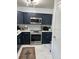 Gorgeous kitchen with stainless steel appliances, navy cabinets, and marble-look tile floors offer modern elegance at 2380 Spring Hollow Drive, Orange City, FL 32763