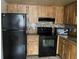 Kitchen featuring wood cabinets, black appliances and mosaic backsplash at 2565 Oak Park Way # 213, Orlando, FL 32822