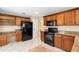 Kitchen with wood cabinets, black appliances, ample counter space, and tile flooring at 2708 Smithfield Dr, Orlando, FL 32837