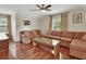 Bright living room featuring wood floors, ceiling fan, large sofas and a glass-topped coffee table at 2770 Red Wing Vlg, Deland, FL 32720