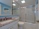 Bathroom with blue walls, granite countertop, and a glass shower door at 2800 N Atlantic Ave # 1716, Daytona Beach, FL 32118
