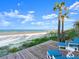 Relaxing beach view from the deck, complete with lounge chairs, palm trees, and sandy shores under a blue sky at 2833 S Atlantic Ave, Daytona Beach, FL 32118