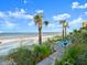 Beautiful beach view with palm trees and blue lounge chairs on a wooden deck near the sandy shore at 2833 S Atlantic Ave, Daytona Beach, FL 32118