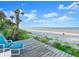 Scenic beach view from the wooden deck, featuring palm trees, blue skies, and sandy shores at 2833 S Atlantic Ave, Daytona Beach, FL 32118