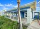 Coastal blue home featuring a spacious brick patio, lush greenery, and a partial ocean view at 2833 S Atlantic Ave, Daytona Beach, FL 32118
