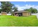 Large backyard featuring lush green grass, shed, white fencing, patio, and mature trees at 3132 Mango Tree Dr, Edgewater, FL 32141