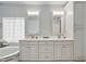 Bright bathroom with dual sink vanity, tiled floors, a soaking tub, and custom cabinetry at 33 Coquina Ridge Way, Ormond Beach, FL 32174