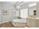 Bright bathroom with dual sink vanity, tiled floors, a soaking tub, and a glass shower enclosure at 33 Coquina Ridge Way, Ormond Beach, FL 32174