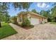 Side view of a one-story home featuring a two-car garage with a brick paved driveway at 33 Coquina Ridge Way, Ormond Beach, FL 32174