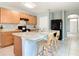 Open kitchen with wood cabinets, black appliances, island with bar seating and tile flooring at 422 Armoyan Way, New Smyrna Beach, FL 32168