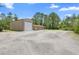 This property includes an oversized tan metal building with a large garage door and ample parking on a gravel driveway at 43350 Natchez St, Deland, FL 32720