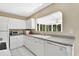 Well-lit kitchen with white cabinetry, granite countertops, and modern appliances with an adjacent sunroom at 441 N Julia Ave, Deland, FL 32720