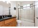 Bathroom showcasing a granite vanity and a shower-tub combo with glass doors at 5445 Turton Ln, Port Orange, FL 32127