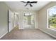 Bedroom features neutral walls and carpet, closet with mirrored doors, a ceiling fan, and lots of natural light at 570 Cypress Ave, Orange City, FL 32763