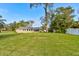 Large backyard with a vast lawn and view of the home's exterior at 65 Sycamore Cir, Ormond Beach, FL 32174