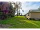 Side yard view shows lush grass, mature trees, and the side of the home at 65 Sycamore Cir, Ormond Beach, FL 32174