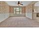 Carpeted dining room with floral wallpaper, a ceiling fan, chair rail, and a glimpse of the kitchen through the doorway at 658 Westchester Dr, Deland, FL 32724
