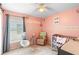 Charming bedroom with pink walls, a crib, and a chair at 824 Casterton Cir, Davenport, FL 33897