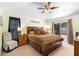 Comfortable main bedroom featuring a ceiling fan and sliding glass doors to the screened lanai at 824 Casterton Cir, Davenport, FL 33897